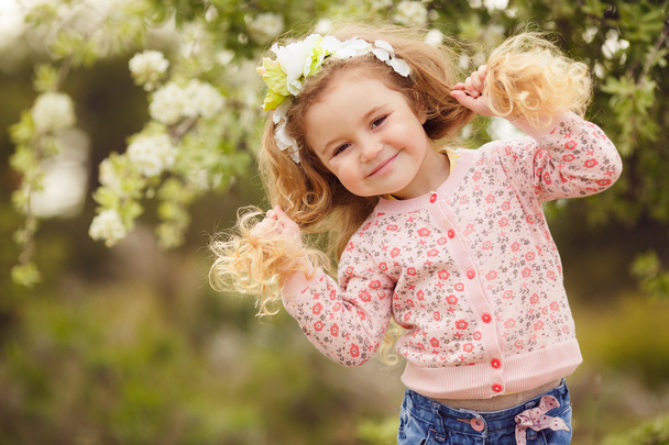 Portrait of little girl outdoors in a lush garden. - Foto, Imagem