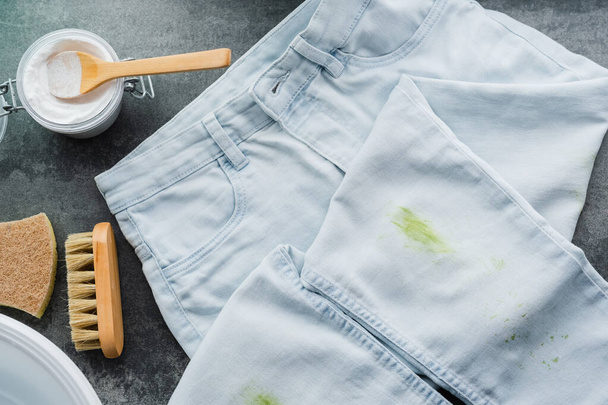 Des taches sales d'herbe verte fraîche sur un jean bleu. Produits de nettoyage naturels. Concept zéro déchet. vue de dessus. Photo de haute qualité - Photo, image