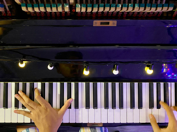 Vista superior hacia arriba del piano clásico brillante negro con la mano del pianista dentro del marco - Foto, Imagen