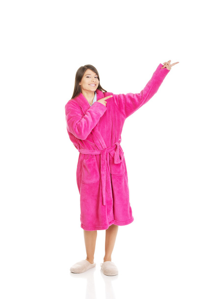 Woman in pink bathrobe pointing aside. - Foto, Bild