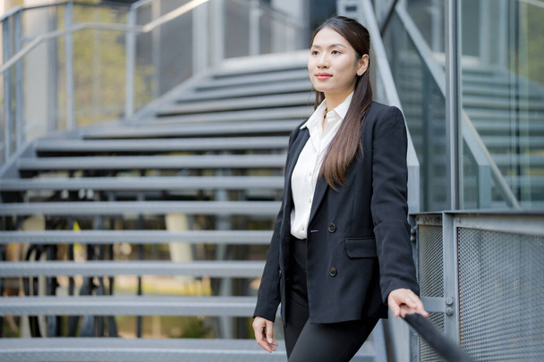 Mujer profesional en un traje sonriente, posado con confianza fuera de un moderno edificio de oficinas - Foto, imagen