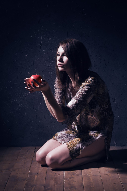 Donna pazza solitaria con mela rossa seduta su un pavimento
 - Foto, immagini