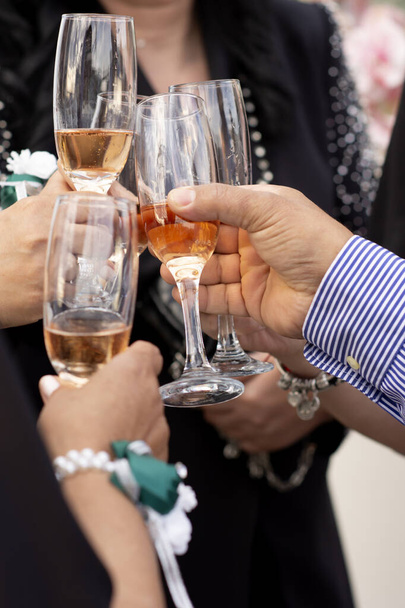 Hands with glasses filled with champagne connect them with the clink of a joyful party event at a social event. - Foto, afbeelding