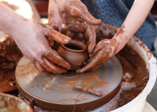 Manos trabajando en la rueda de cerámica
 - Foto, imagen