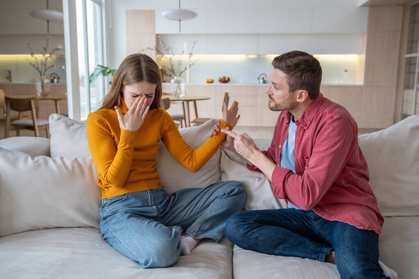 Nervous aggressive emotional husband threatening helpless unhappy wife. Stressed female crying, closing face with hand. Conflict, harassment, crisis, arguing, home violence, jealousy in family life - Photo, image