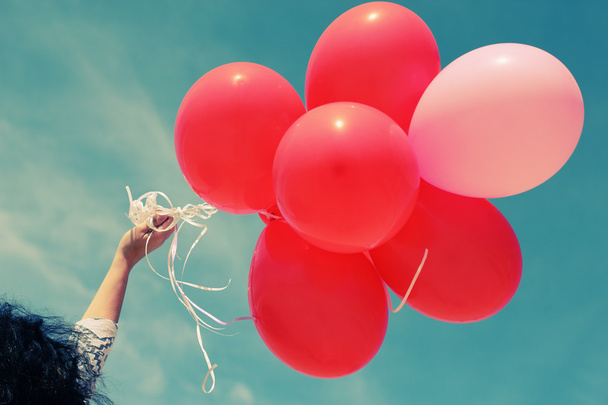 Mão segurando balões vermelhos
 - Foto, Imagem