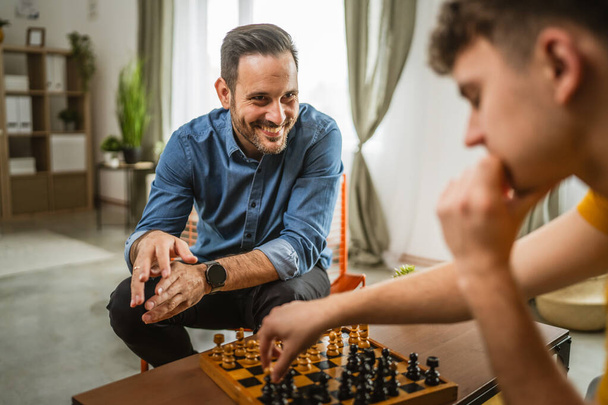 homem branco jovem e adulto amigos, primos ou irmãos jogar xadrez juntos em casa - Foto, Imagem