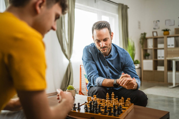 homem branco jovem e adulto amigos, primos ou irmãos jogar xadrez juntos em casa - Foto, Imagem