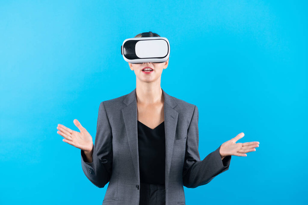 Mujer de negocios calificada caucásica explicando mientras usa gafas VR. Gerente de proyecto cualificado que utiliza la innovación de la realidad visual mientras está parado en el fondo azul. Tecnología futurista. Artilugio. - Foto, Imagen