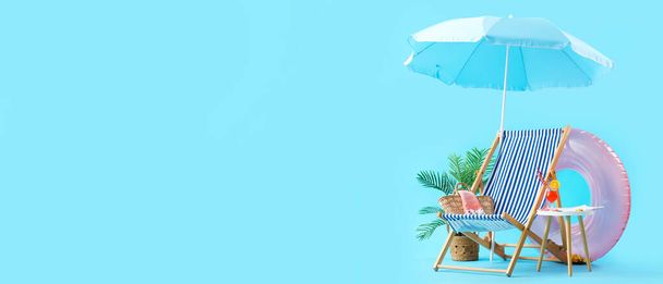 Deck chair, umbrella and beach accessories on blue background with space for text - Фото, изображение