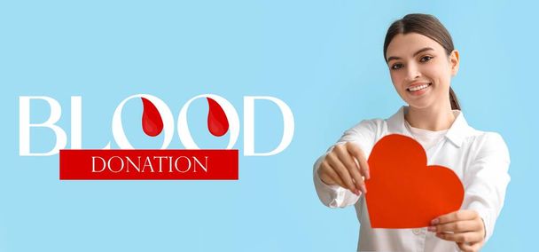 Banner for World Blood Donor Day with young female doctor holding paper heart - Photo, Image