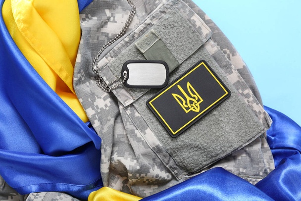 Vojenská uniforma s odznakem ukrajinské armády, visačka a vlajka Ukrajiny na tyrkysovém pozadí - Fotografie, Obrázek