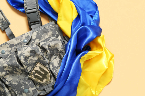 Vykládání vesta s odznakem ukrajinské armády a Ukrajiny vlajky na béžovém pozadí - Fotografie, Obrázek