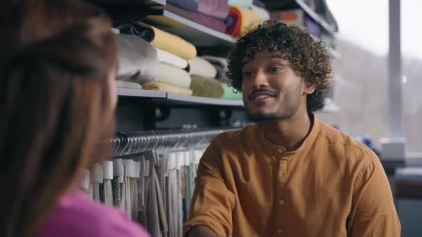 Щасливий індійський арабський дизайнер моди розмовляє з кавказьким клієнтом у магазині тканин чоловічої руки багаторасовий чоловік жінка трясе руки угода продажу текстильних покупок в ательє - Кадри, відео