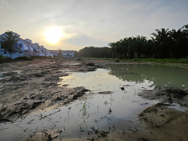 Szene eines leeren reflektierenden Pools aus stehendem schlammigem Regenwasser am Wohngebiet. - Foto, Bild