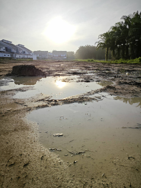 scena pustego refleksyjnego basenu stagnacji błotnistej ziemi deszczowej przy dzielnicy mieszkalnej. - Zdjęcie, obraz