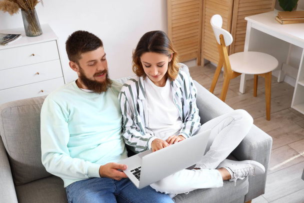 Szczęśliwa para w miłości za pomocą laptopa na kanapie w domu - Zdjęcie, obraz