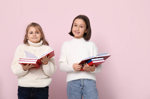 Маленькие девочки читают книги на розовом фоне - Фото, изображение