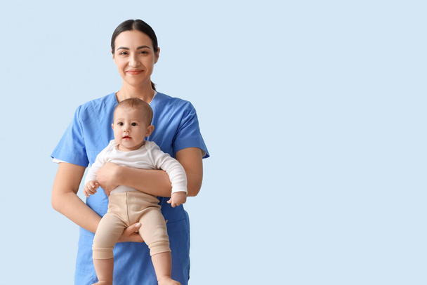 Female pediatrician with little baby on blue background - Foto, immagini