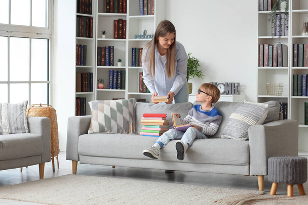 Mignon petit garçon et sa mère avec différents livres à la maison - Photo, image