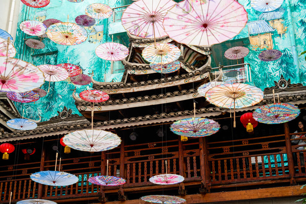 Many Chinese oil-paper umbrellas hang on ancient Chinese buildings - Photo, Image