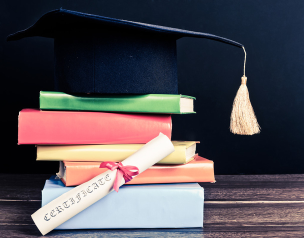 A mortarboard and graduation scroll on books - Foto, Imagem