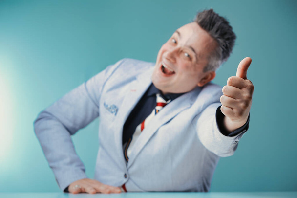 Радостный бизнесмен дает большой палец вверх, его лицо излучает энтузиазм и позитивность в профессиональной обстановке - Фото, изображение