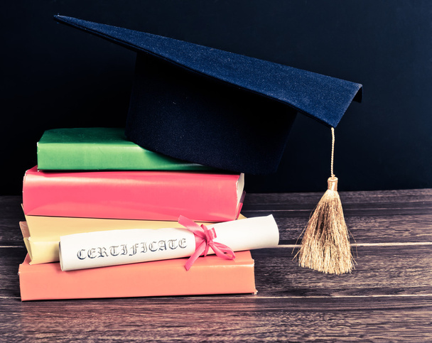 A mortarboard and graduation scroll on books - Foto, afbeelding
