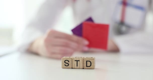 O médico está a guardar preservativos e a palavra "DST" fecha. Conceito de doenças sexualmente transmissíveis - Filmagem, Vídeo