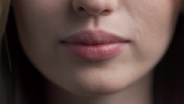 Κοντινό πλάνο των χειλιών μιας γυναίκας που στέλνει ένα φιλί στον αέρα. Όμορφα ροζ χείλη μιας νεαρής Καυκάσιας. τέλειο υπόβαθρο για την κοσμετολογία. - Πλάνα, βίντεο