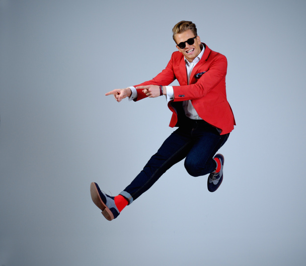 Стильний чоловік в червоній куртці весело стрибає
  - Фото, зображення