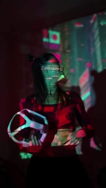 Sanal gerçeklik gözlüklü genç bir kadın renkli ışıklar arasında dans ediyor. Yüksek kalite 4k görüntü - Video, Çekim