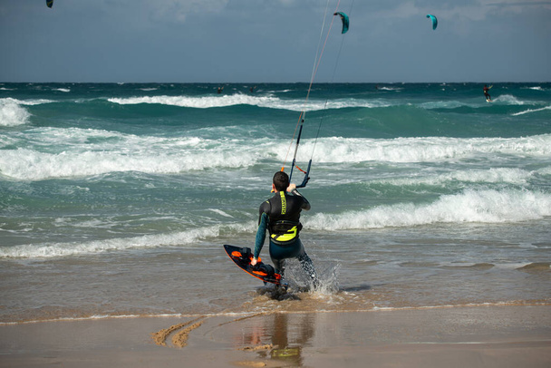 Uçurtma. Sörfçüler Akdeniz 'in dalgalarında çeşitli numaralar yaparak sörf yaparlar. İsrail Ashkelon 26 Kasım 2023 - Fotoğraf, Görsel