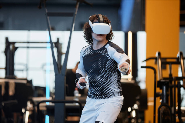 Портрет чоловіка в гарнітурі VR в спортзалі, насолоджуючись захоплюючою спритністю тренувального простору копіювання - Фото, зображення