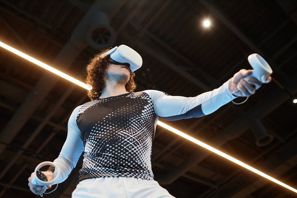 Futurisztikus alacsony szögű lövés az ember visel VR headset tornaterem és a képzés ellen neon fénycsík fénymásoló hely - Fotó, kép
