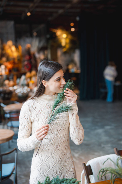A young woman crafting a festive wreath during a decor-making seminar. High quality photo - Photo, Image