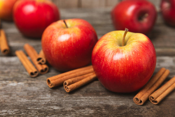 Äpfel mit Zimt auf einem strukturierten Holzgrund. Duftende rote würzige Äpfel mit Zimtstangen und Sternanis. Apfelscheiben mit würzigen Gewürzen. Platz für Text. Kopierraum. Ernten. Früchte.  - Foto, Bild
