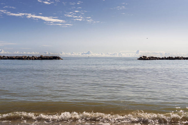 Paisaje marino tranquilo con olas suaves y un muelle rocoso bajo un vasto cielo, perfecto para temas de paz, belleza natural y serenidad - Foto, Imagen