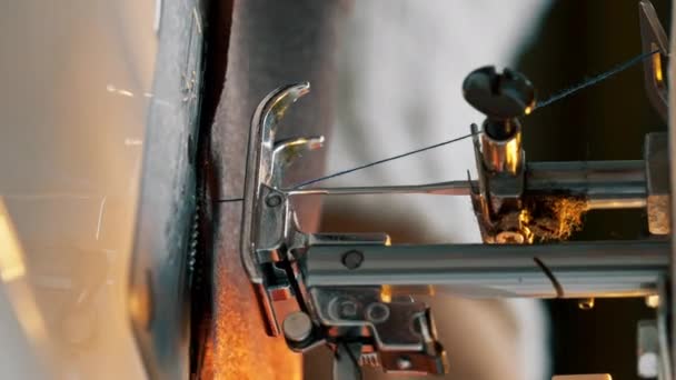 vídeo vertical de cerca en un taller de costura en una máquina de la costurera maestro hace corte en tela negra - Metraje, vídeo