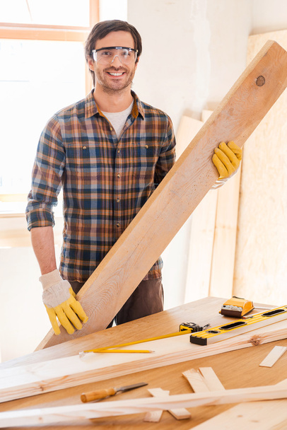 Carpenter holding wooden plank in workshop - Zdjęcie, obraz