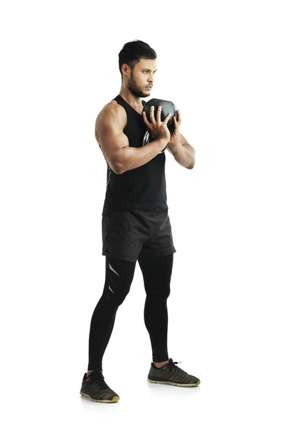 Man, fitness and training with kettlebell in studio for muscle, endurance and healthy body. Gym, equipment and serious person with strength for resilience, exercise and workout on white background. - Photo, image