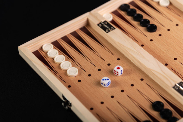 Tavola per giocare a backgammon con pezzi e dadi su sfondo nero. Gioco da tavolo, passatempo, divertimento. - Foto, immagini