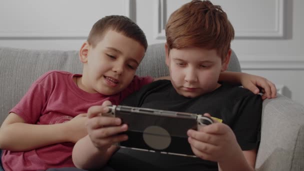 Los adolescentes se relajaron jugando en videojuegos en casa. Niño y su hermano disfrutando de nuevas características del juego. Controlador inalámbrico de mando. Mejor amigo apoyar a su hermano en juegos de consola - Imágenes, Vídeo