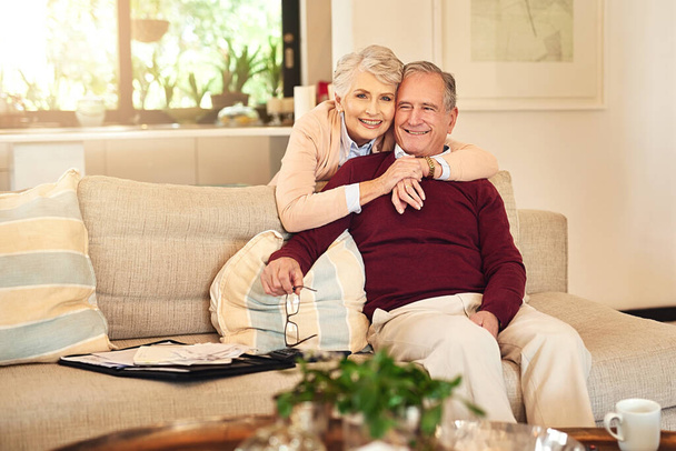 Hug, love and portrait with senior couple on sofa in living room of retirement home together for bonding. Happy, relax or smile with old man and woman in apartment for commitment, marriage or weekend. - Photo, Image