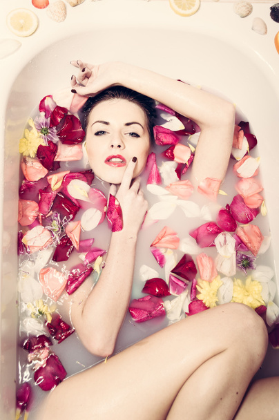 woman in bath with flowers petals - Foto, afbeelding