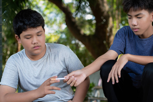 Nastolatki palące papierosa powodują złe nawyki powodujące uzależnienie. Azji schooboy palenie problemów, uczucie smutku, nieszczęśliwy i depresji, podkreślił w starym brudnym grungy miejscu. - Zdjęcie, obraz
