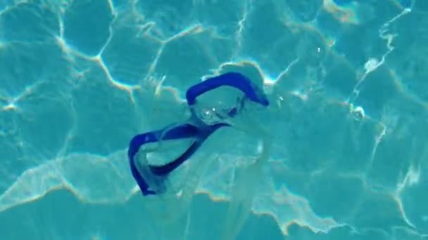 Een zwemmasker drijvend helder water. Geïsoleerd masker, zonnige sammer dag: 4k video, slow motion. - Video