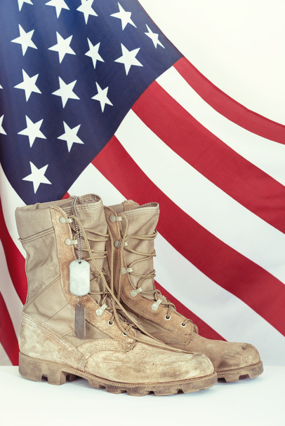 Old combat boots and dog tags with American flag - 写真・画像