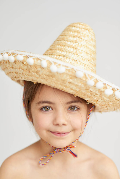 Fashion, straw hat and portrait of child in studio with traditional Mexican costume for halloween. Smile, confident and girl kid with accessory for cosplay, dress up or apparel by gray background - Photo, Image