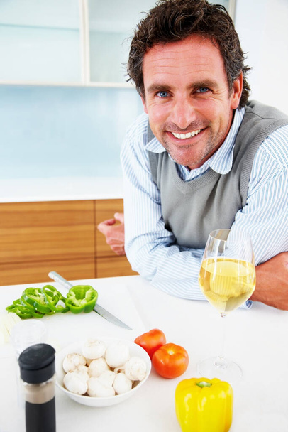Portrait, smile and man cooking vegetables with wine for healthy diet, food or nutrition in home. Face, kitchen and happy person meal prep for dinner or organic salad with alcohol drink in Sweden. - Foto, afbeelding